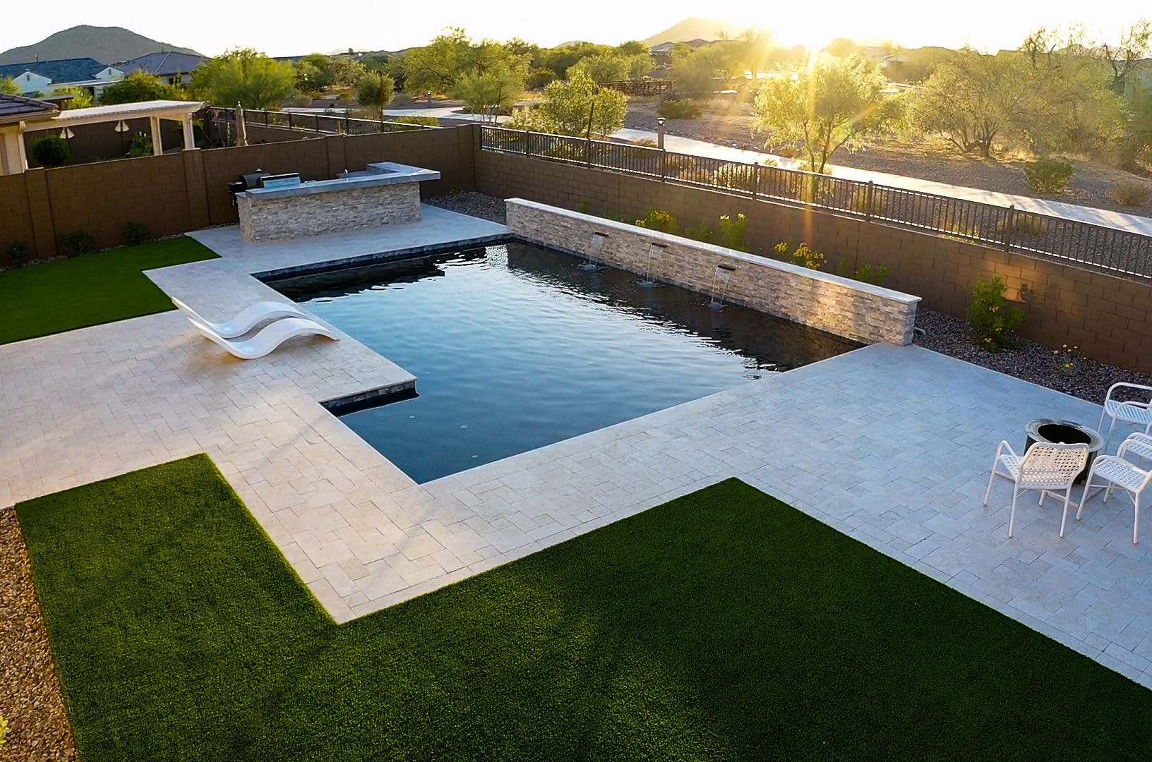 Aerial view of freeform pool with paver patio, fire feature, and mature landscaping