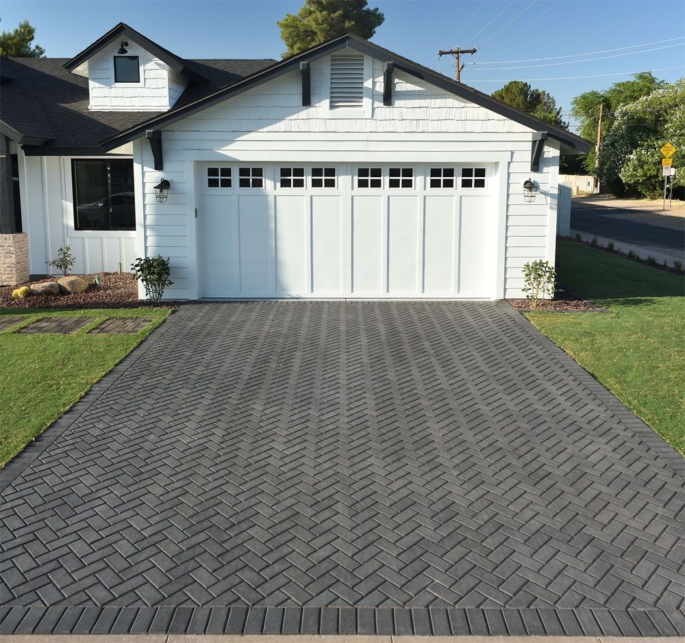 Modern white farmhouse with herringbone paver driveway