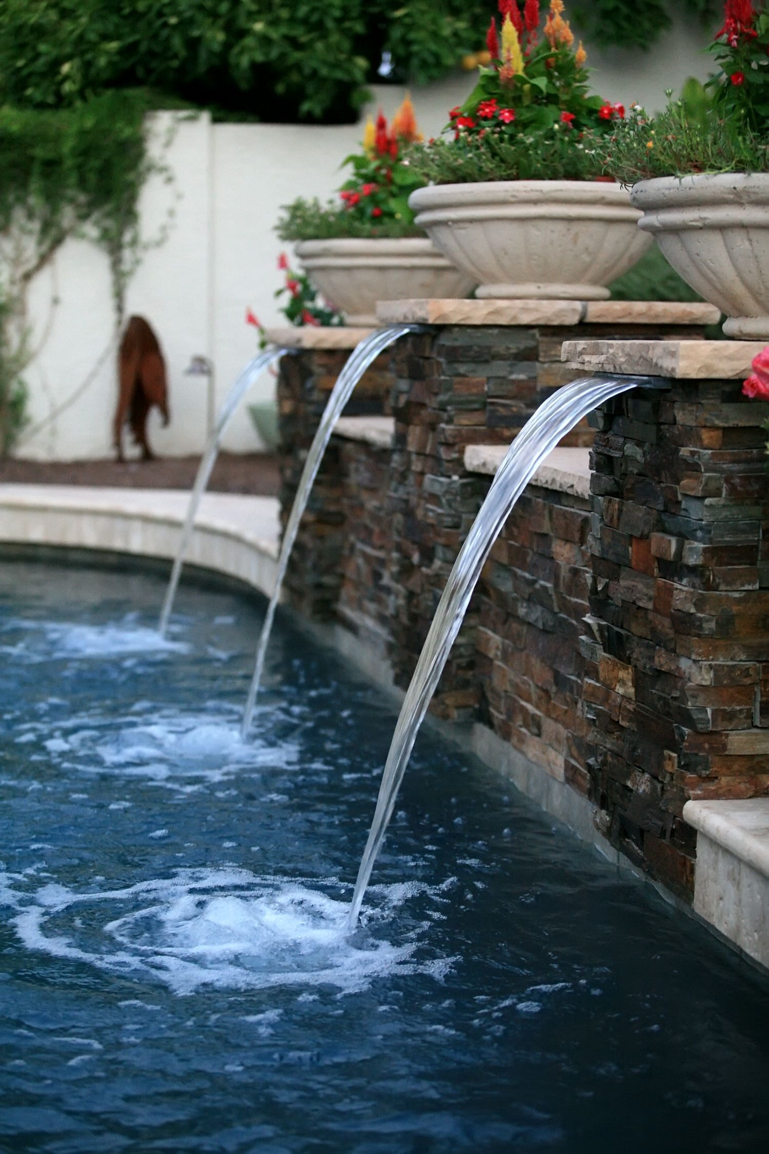 Natural stone water feature with cascading waterfalls into pool